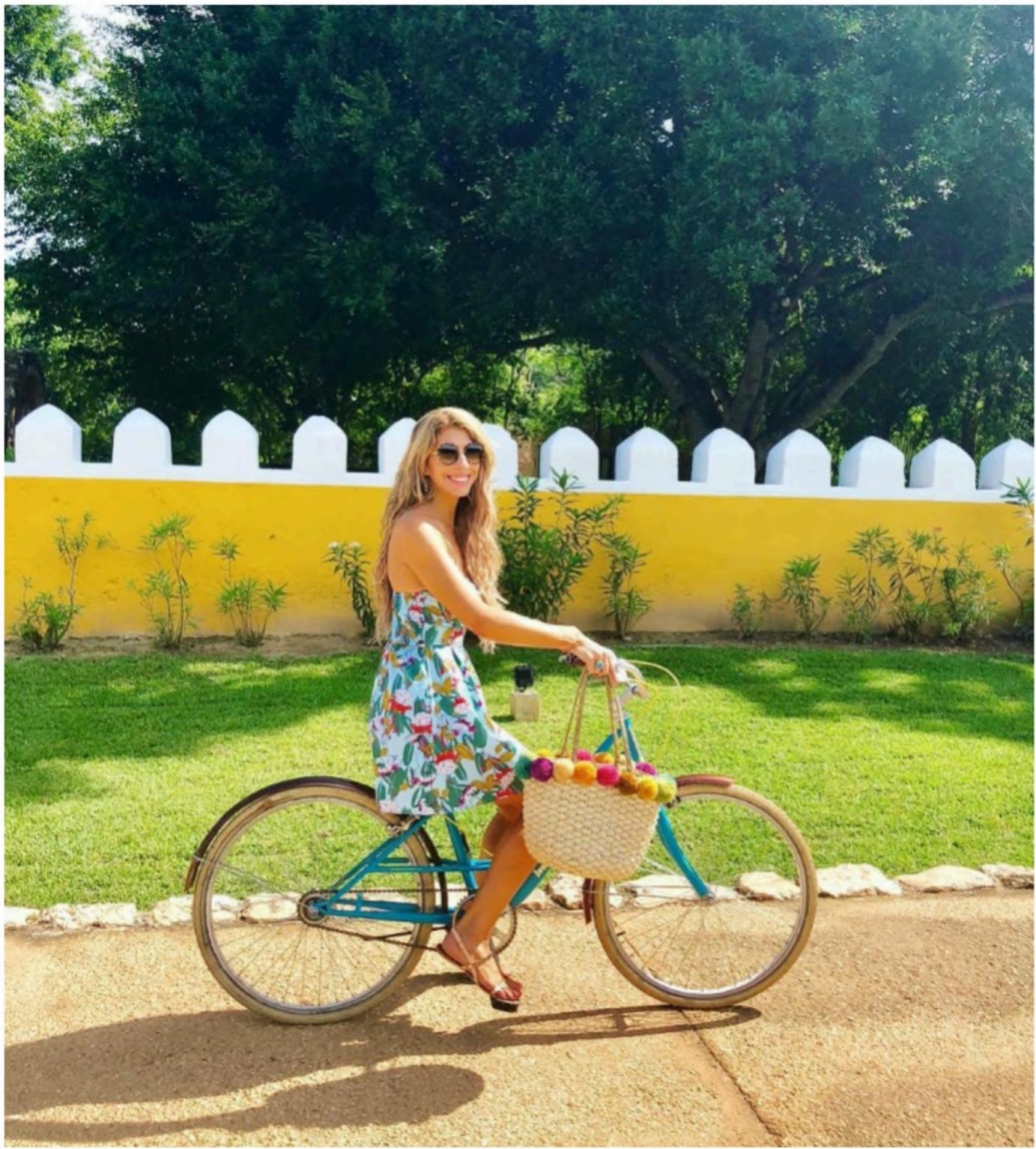 Dr. Kerry Pittman in a floral dress on a blue bicycle